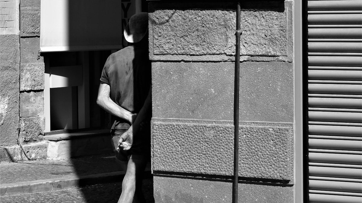 a man walking past a tall building next to a street sign