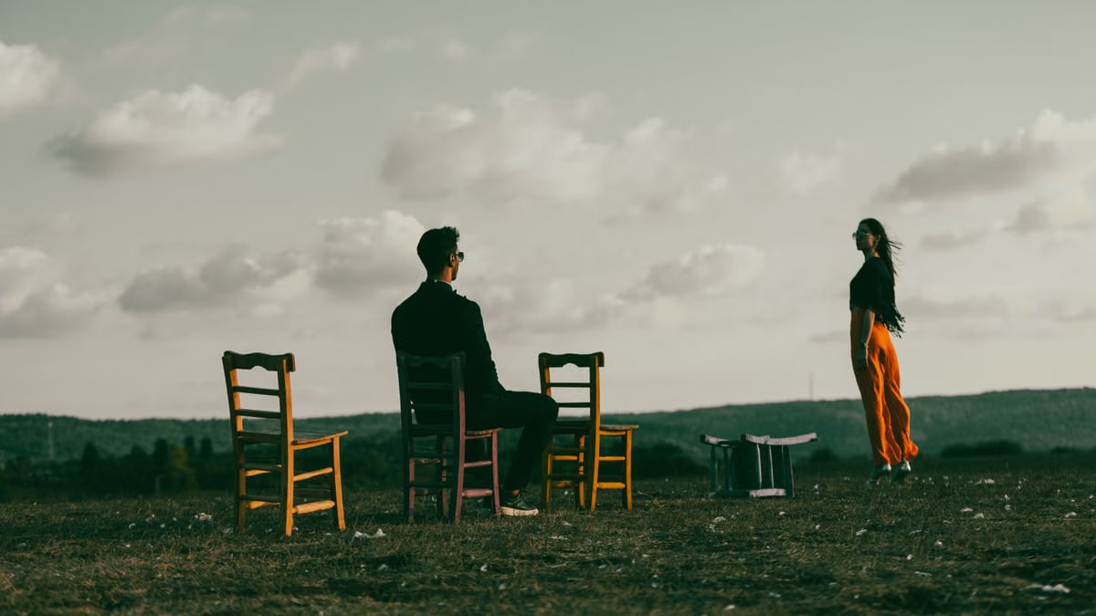 Two people in a serene outdoor setting with chairs, capturing introspection and tranquility.